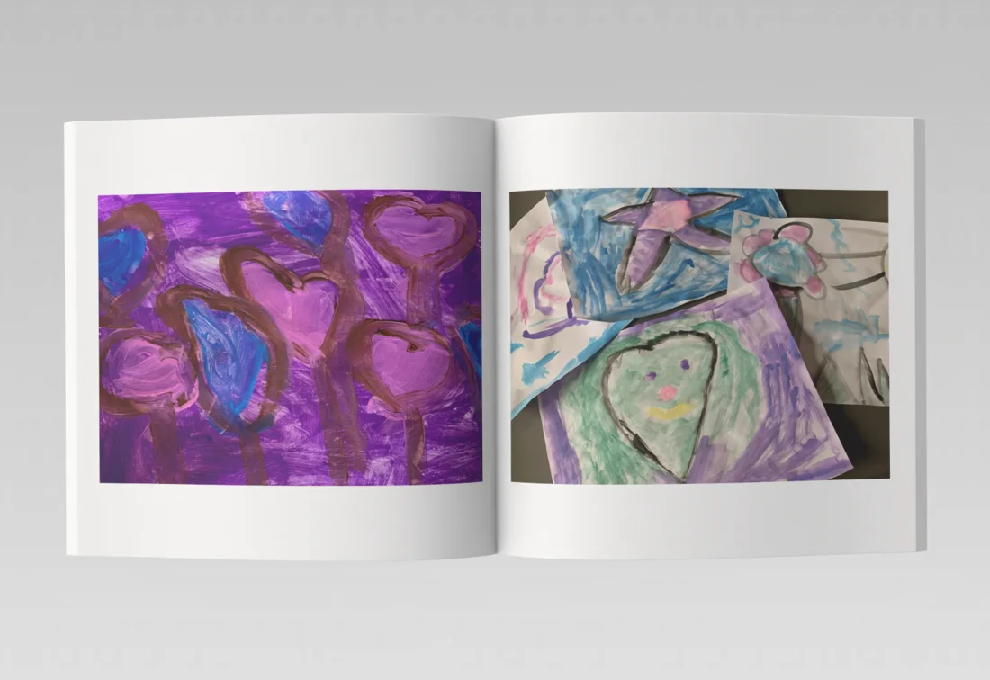 An open Artbox photo book with colorful children’s paintings across its pages